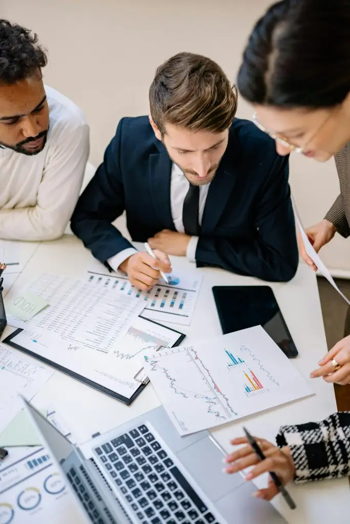 Business professionals collaborating over charts and laptops in an office.